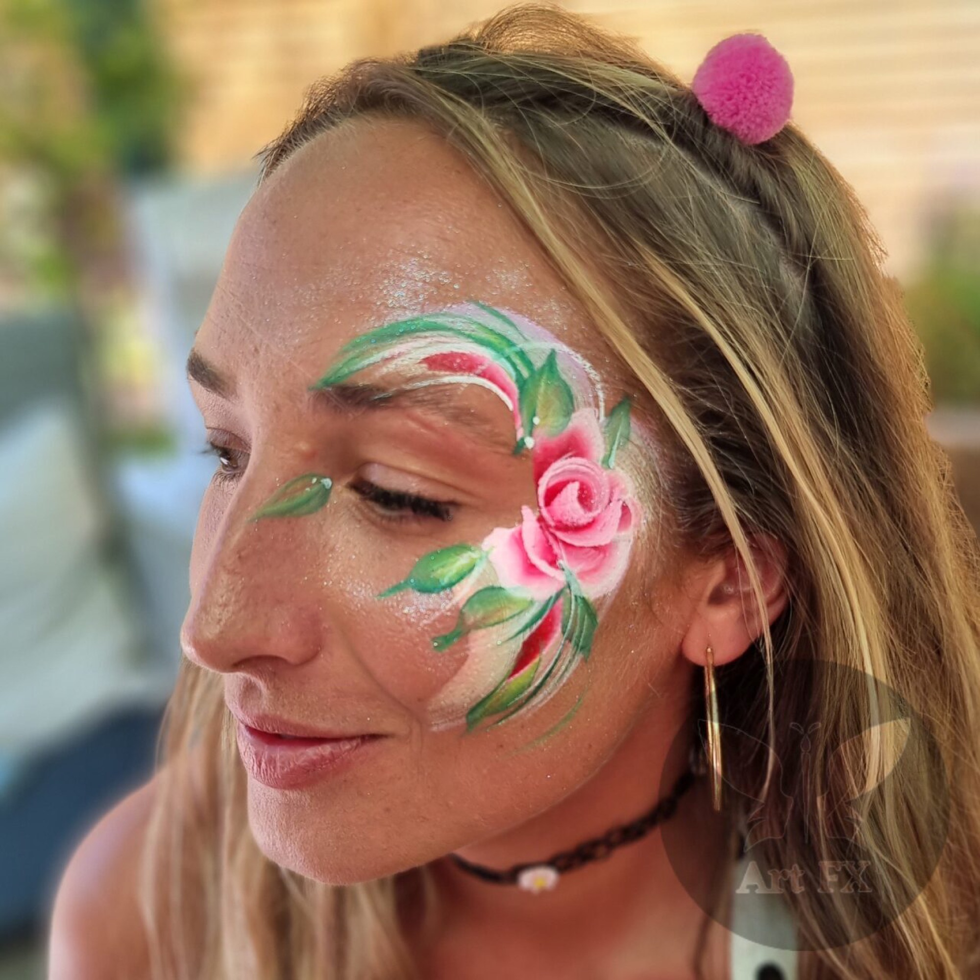 Adult woman smiling, simple and elegant pink rose face painting design on her cheek