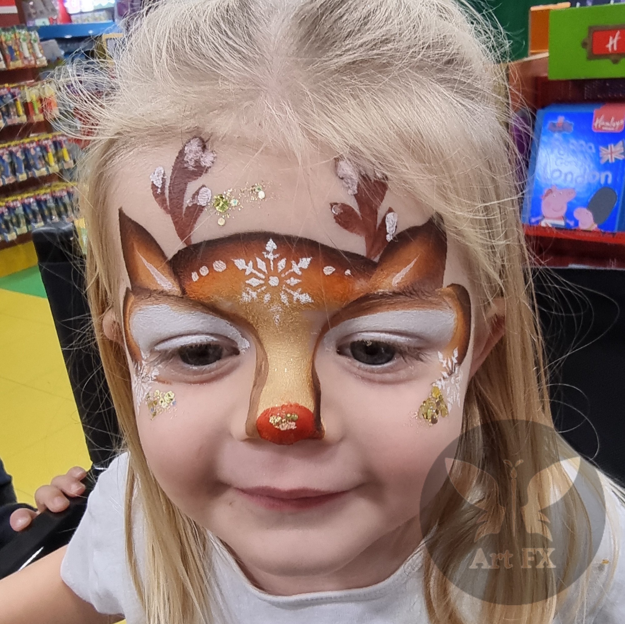Reindeer face paint on a girl with antlers and a red nose.