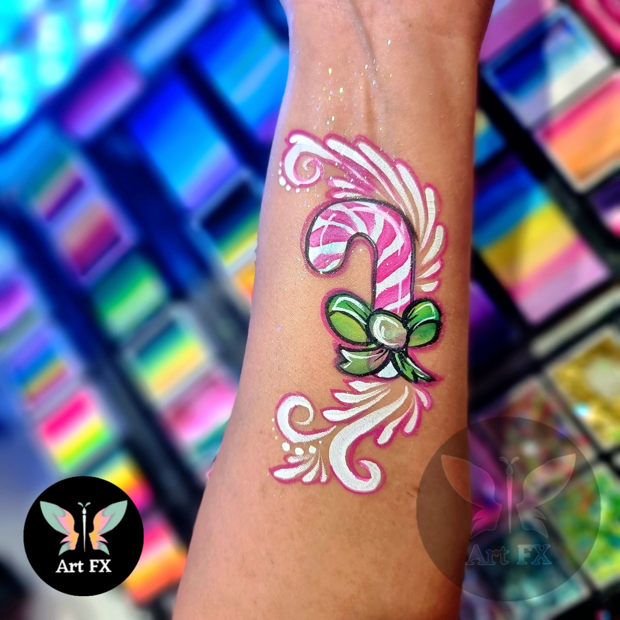 Candy cane body paint on an arm with a green bow.