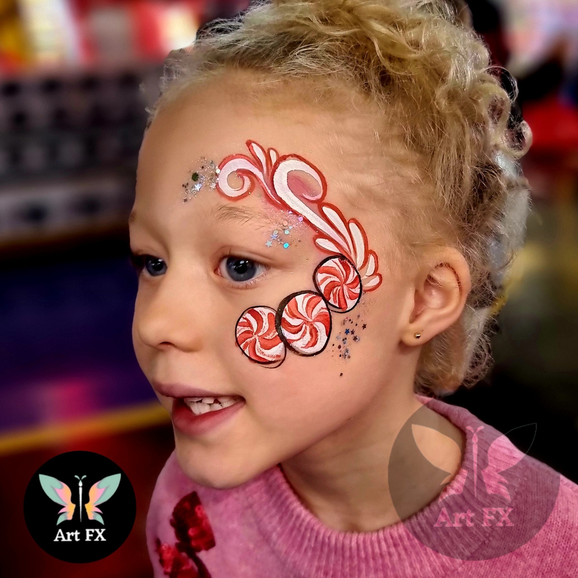 Peppermint swirl candy face paint on a girl's cheek.