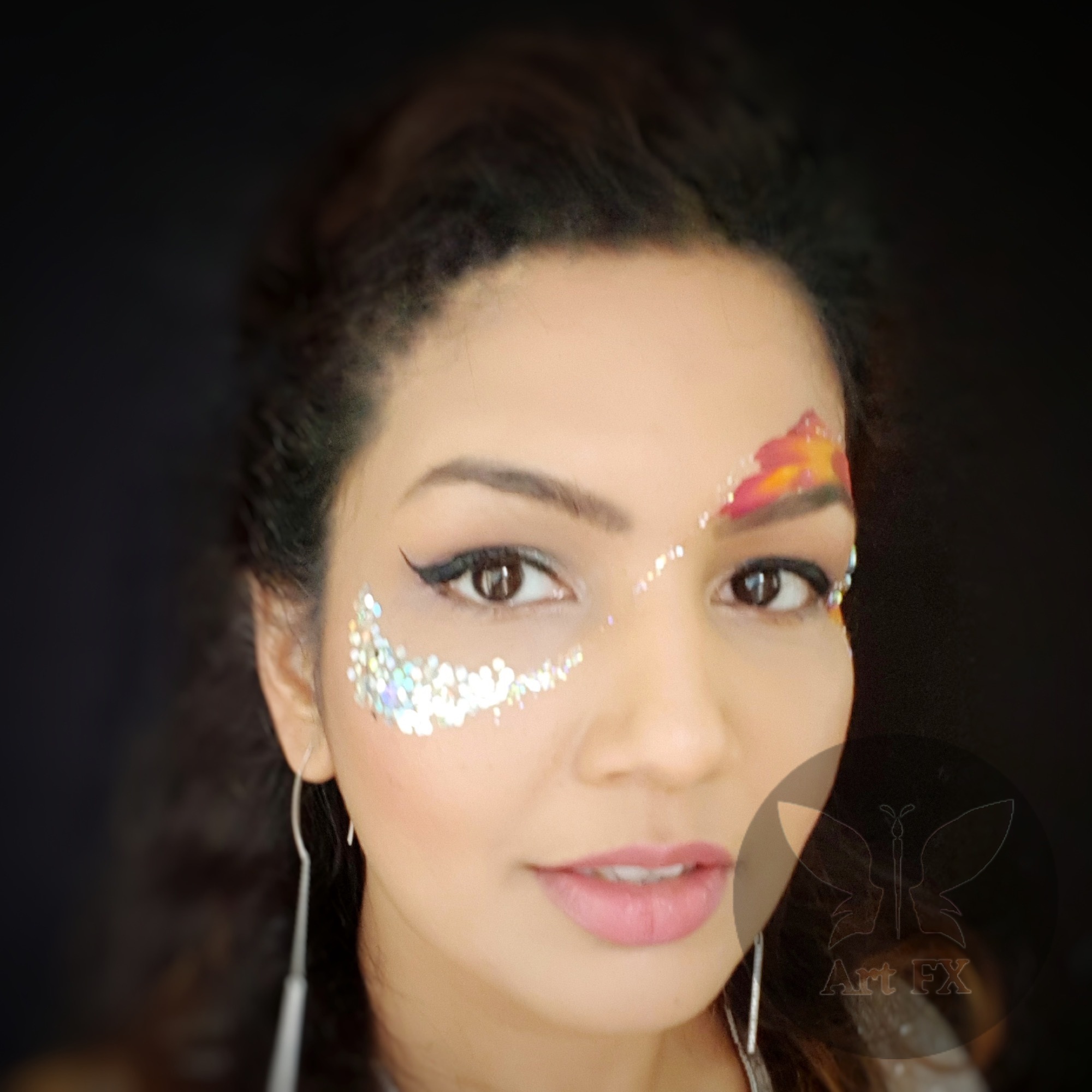 A festival goer with a striking pink and gold floral face paint design embellished with chunky pink glitter and sequins.