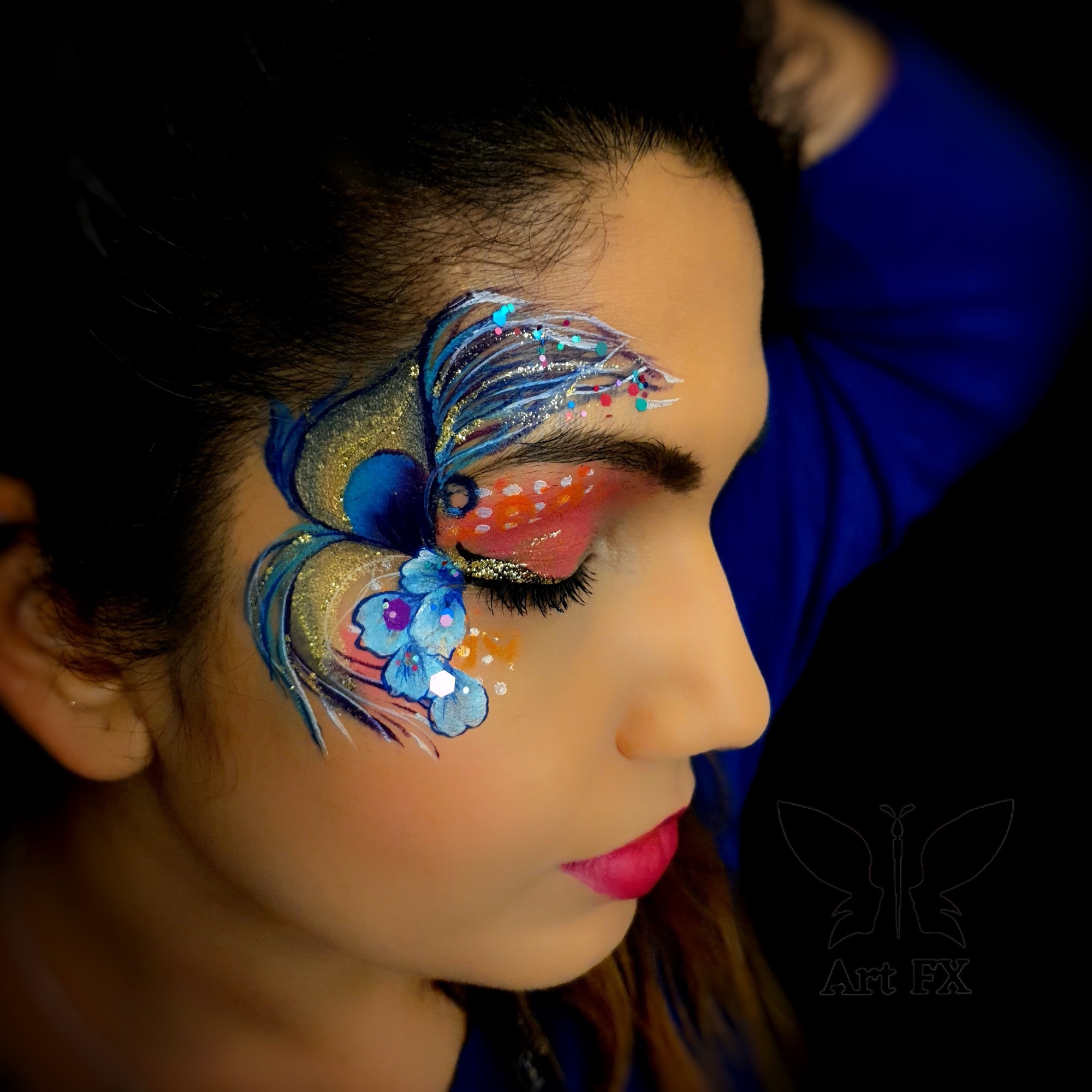 A woman with a striking purple and magenta floral face paint design featuring dark accents and chunky silver glitter.