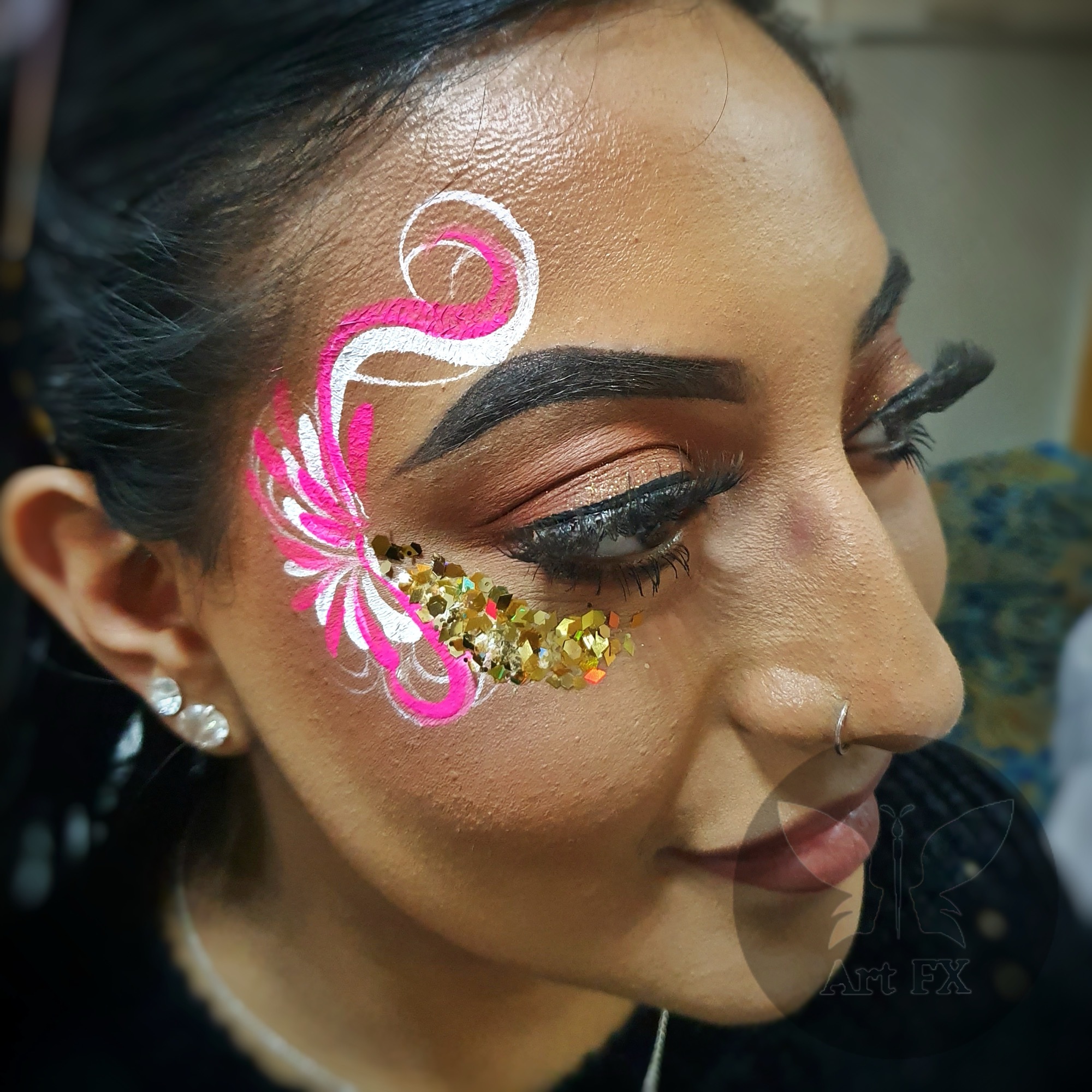 A festival attendee with a stunning colorful floral face paint design in pink, orange, and purple with star glitter.