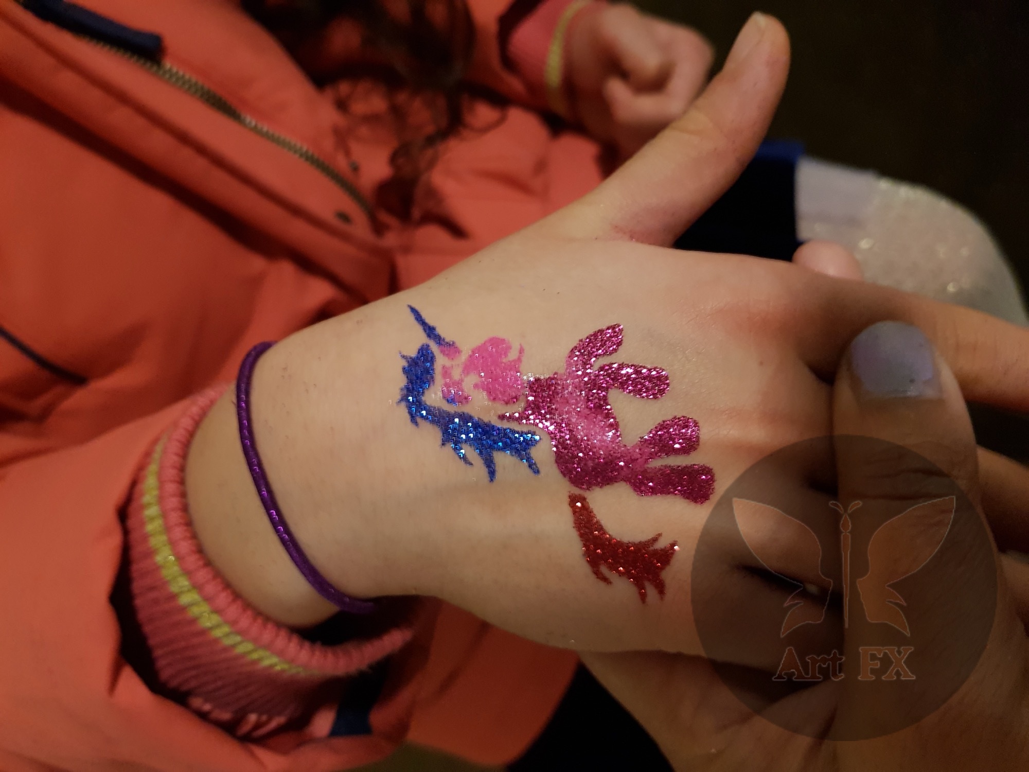 Pink and blue glitter tattoo of a My Little Pony character on a hand.