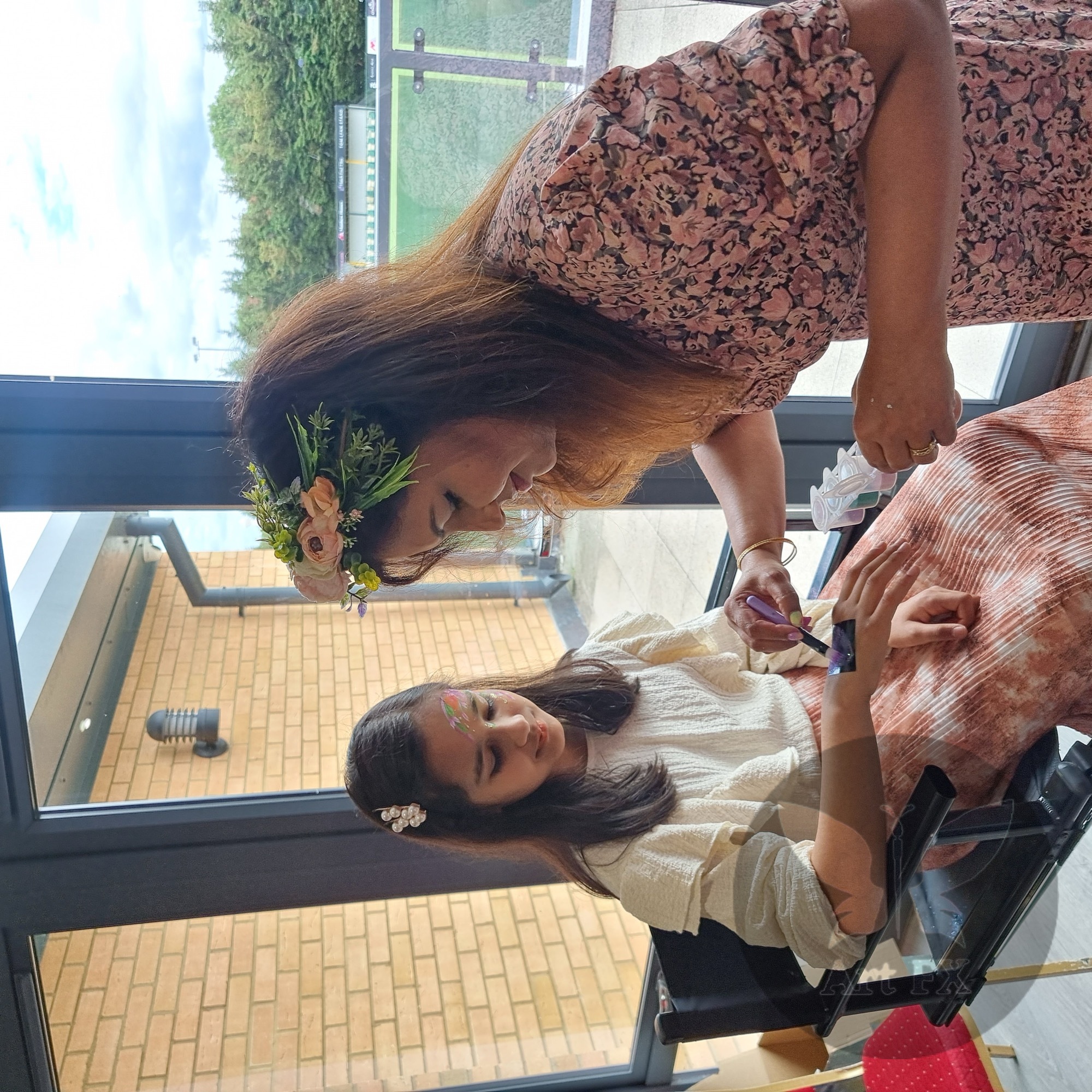 Close-up of Shailee applying a delicate glitter design to a girl's arm at a private party.