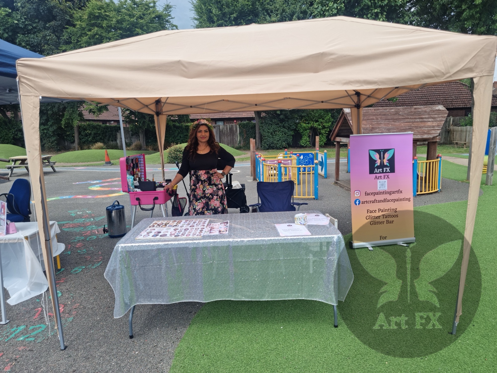 Shailee standing at her face painting station under an outdoor marquee, ready to paint at a community event.