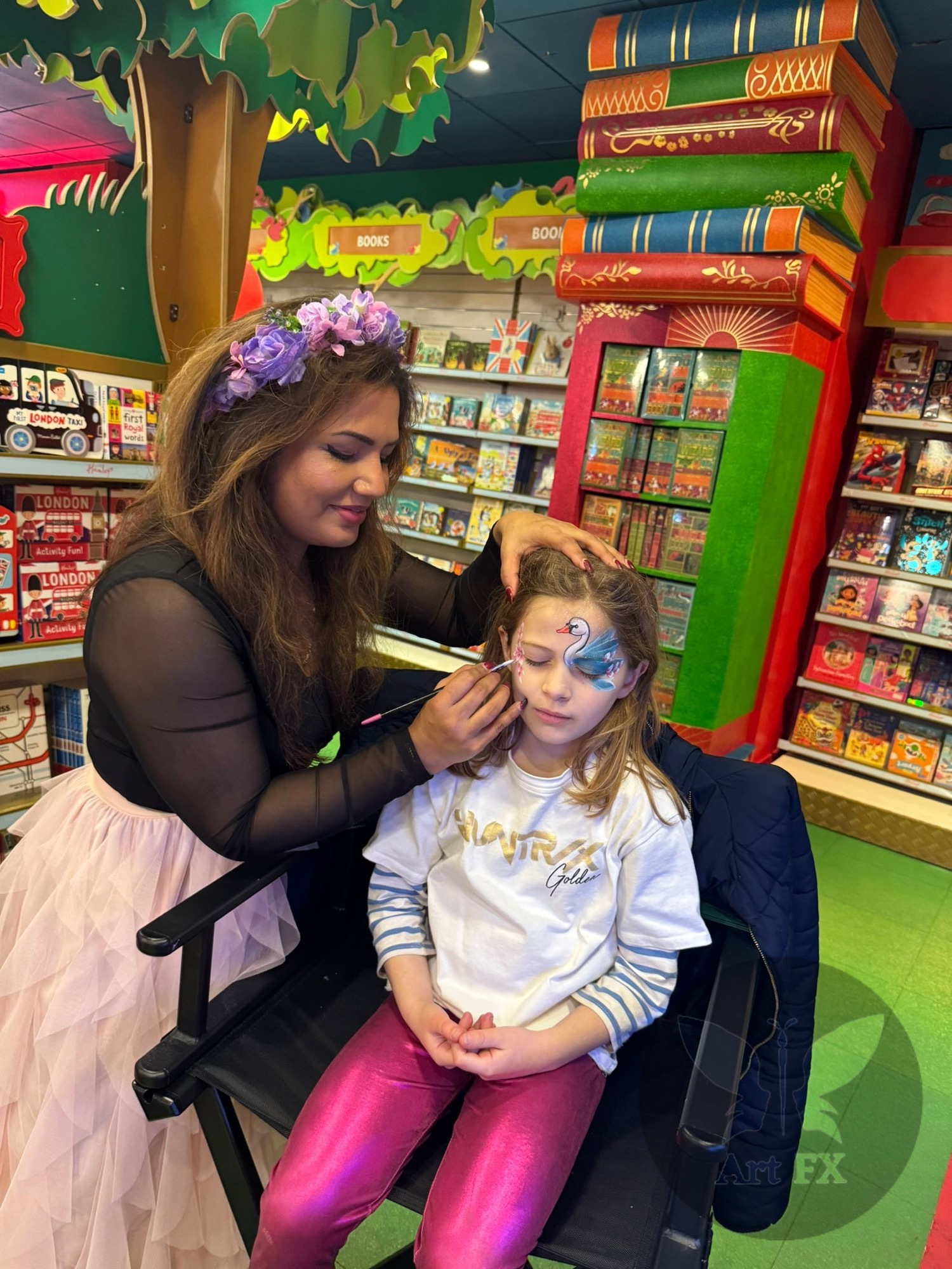 Shailee applying an elegant swan face paint design to a young girl at a themed event.