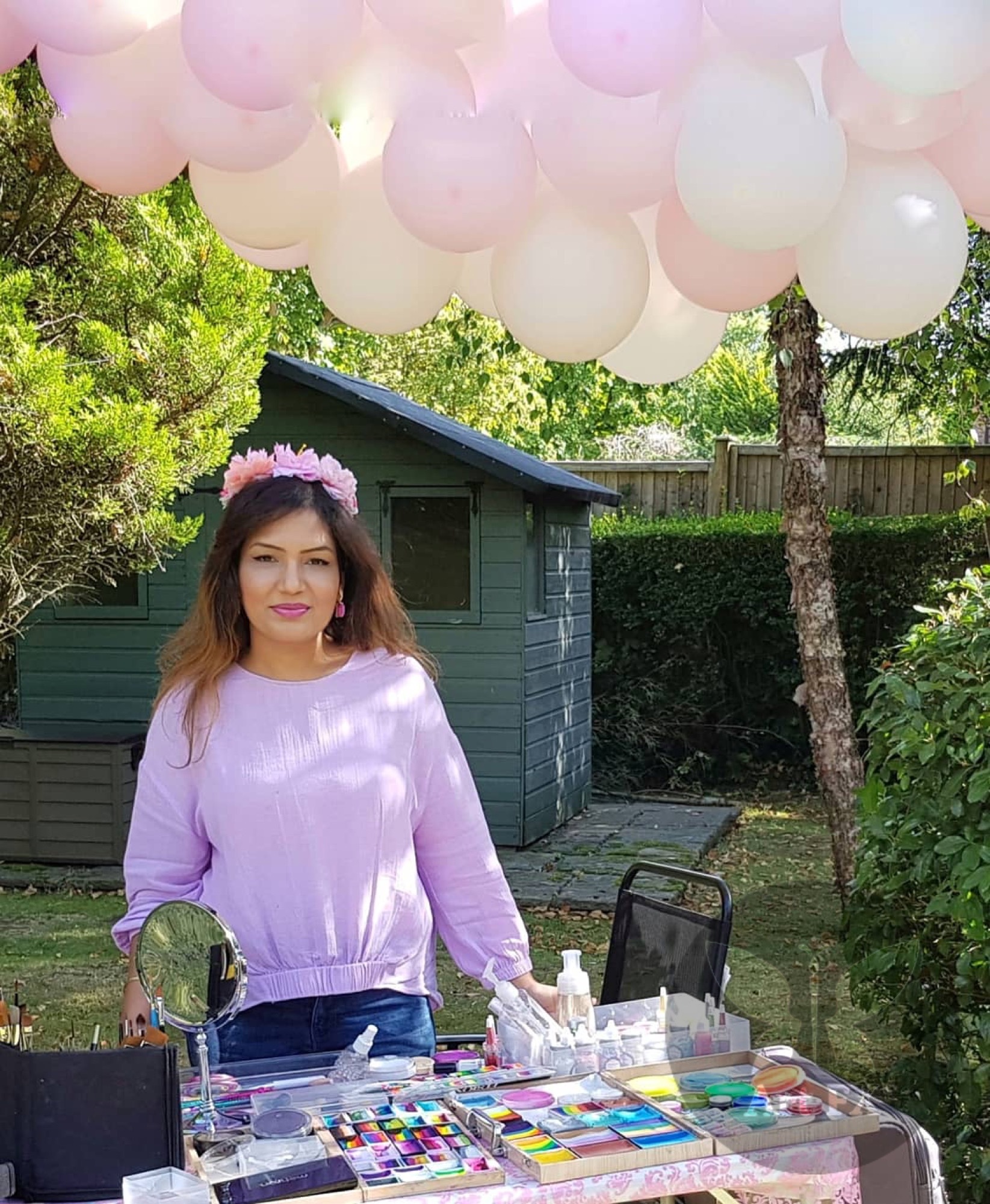 Shailee at her face painting table decorated with pink balloons, ready for a birthday party.