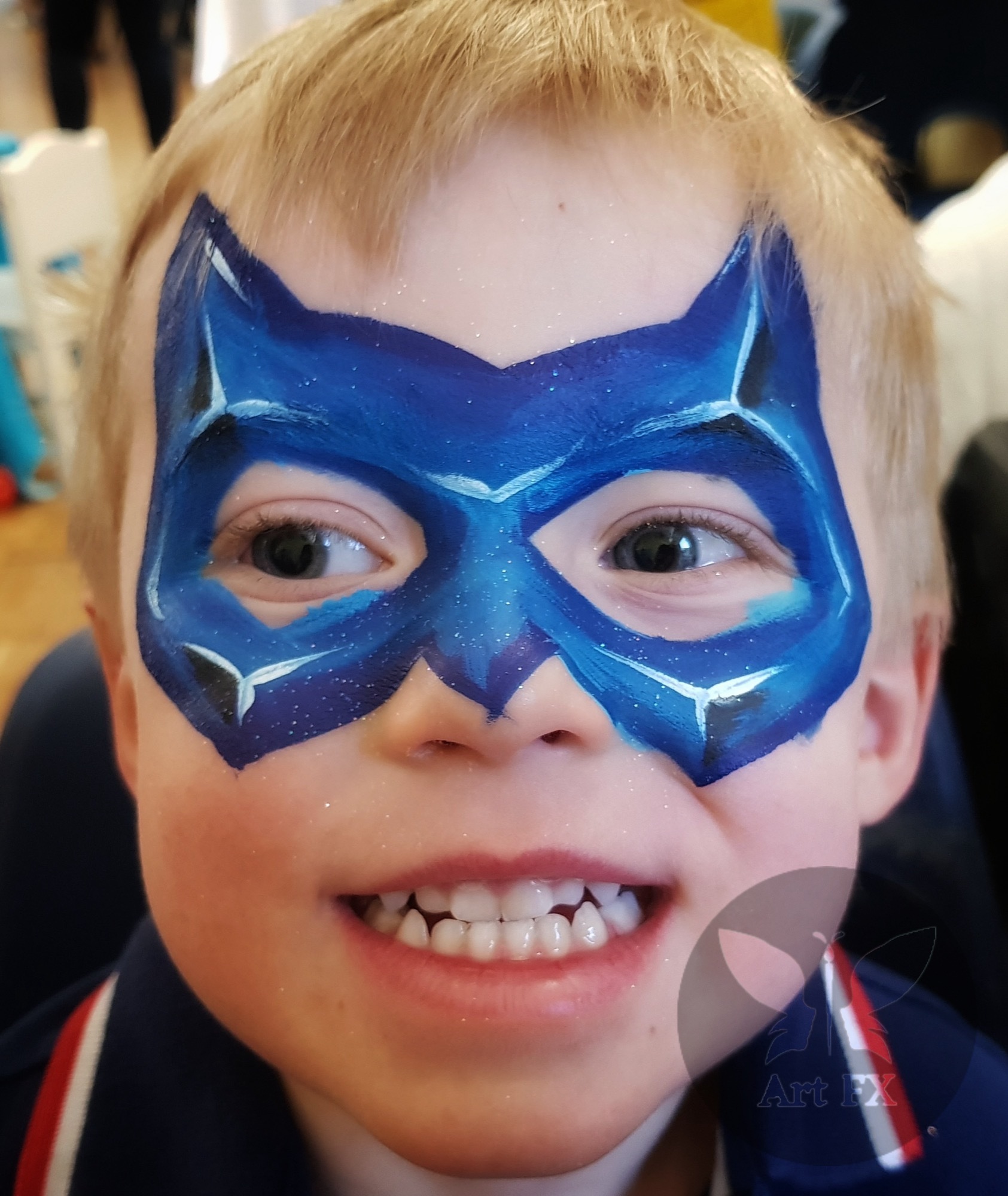 Young girl featuring a pink and purple butterfly face painting design with floral and swirl details