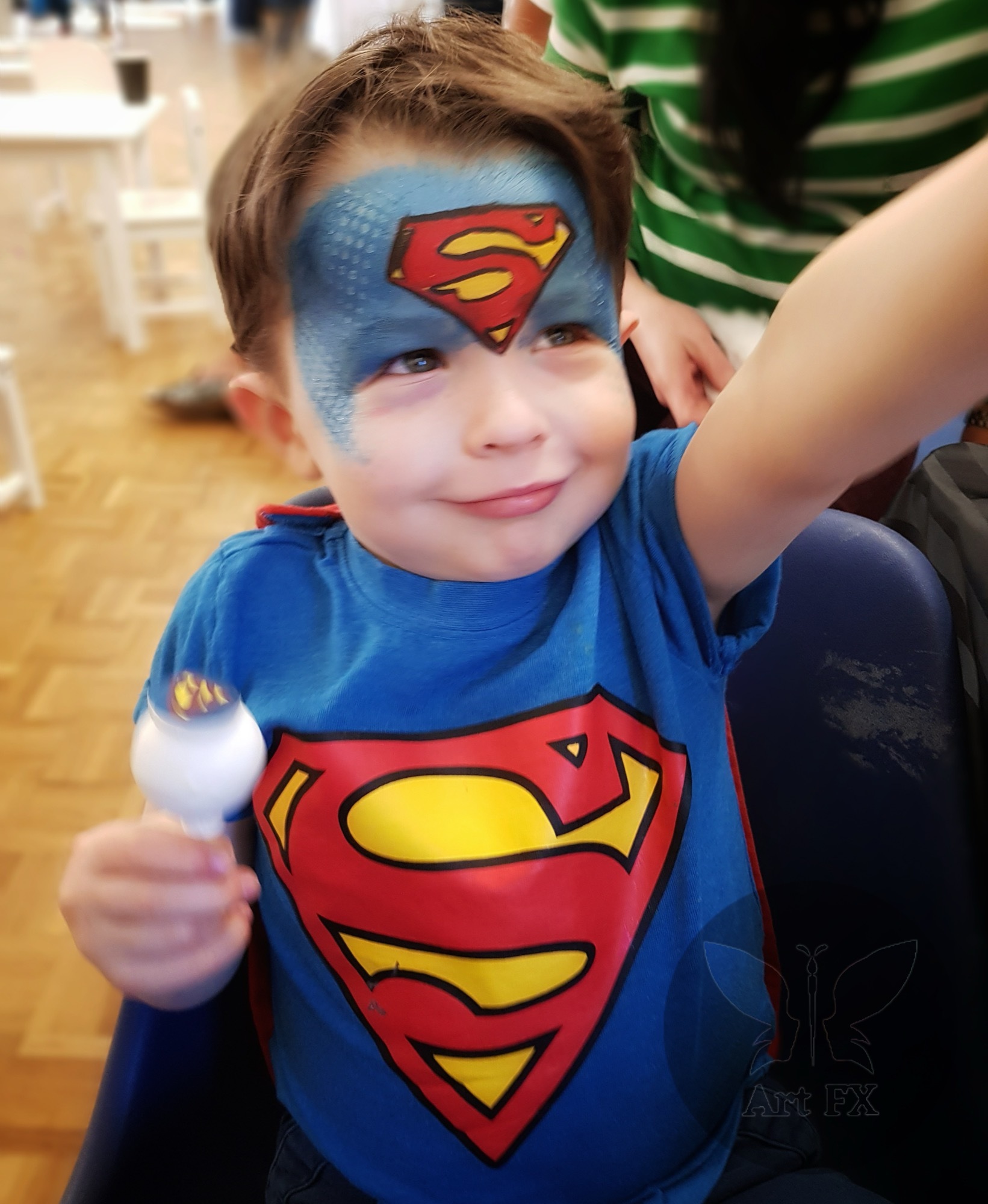 Young boy showcasing a green and black comic book superhero mask face painting design