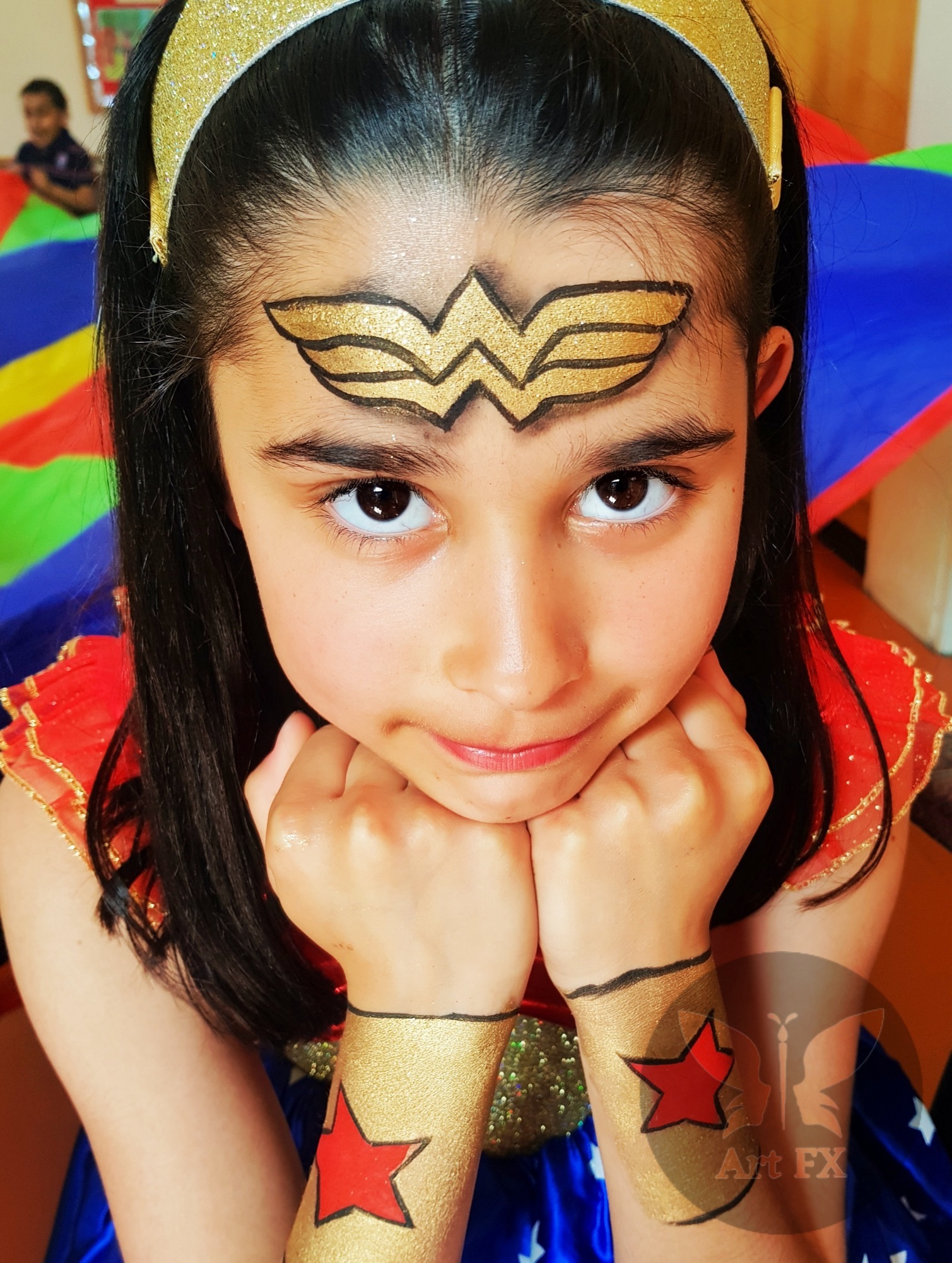 Young girl with a delicate pink and purple butterfly face painting design featuring glitter accents