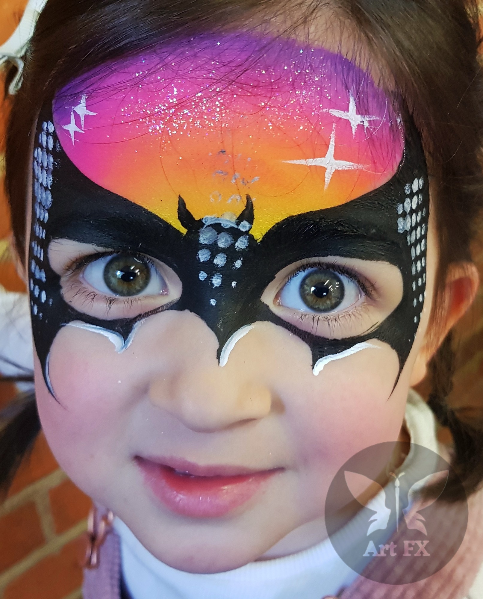 Young boy showcasing a bold half-face green superhero mask face painting design