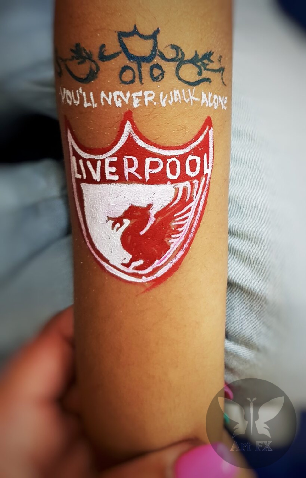 Young girl with an elegant pink floral butterfly face painting design featuring white swirls and glitter