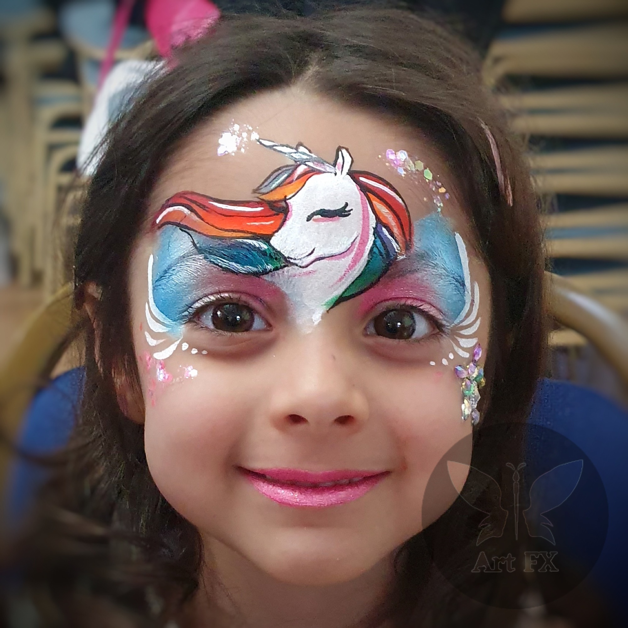 Young girl showcasing a bright pink butterfly and floral face painting design with white highlights