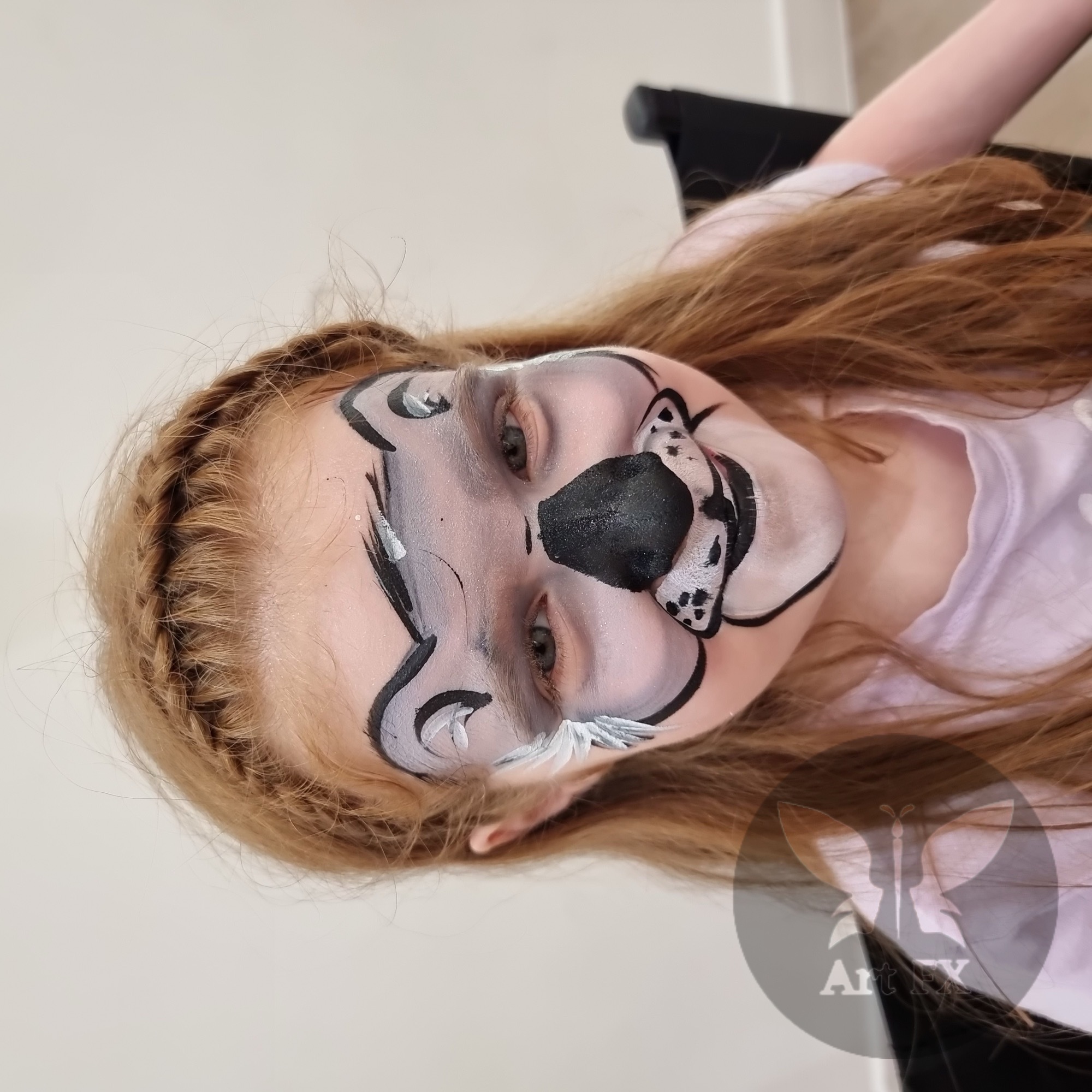 Young girl featuring an elegant pink unicorn face painting design and floral crown details