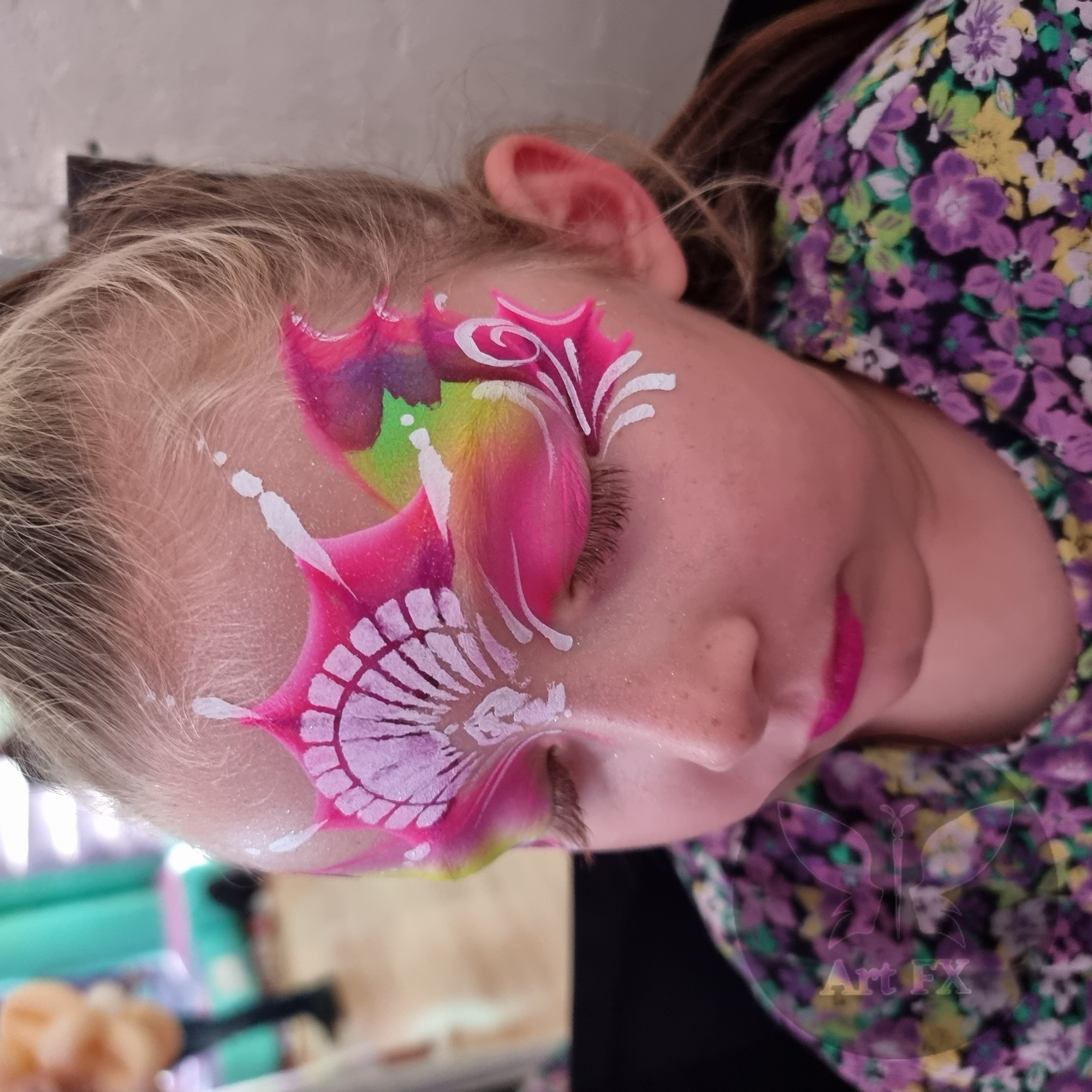 Young boy featuring a dynamic blue and yellow superhero lightning mask face painting design