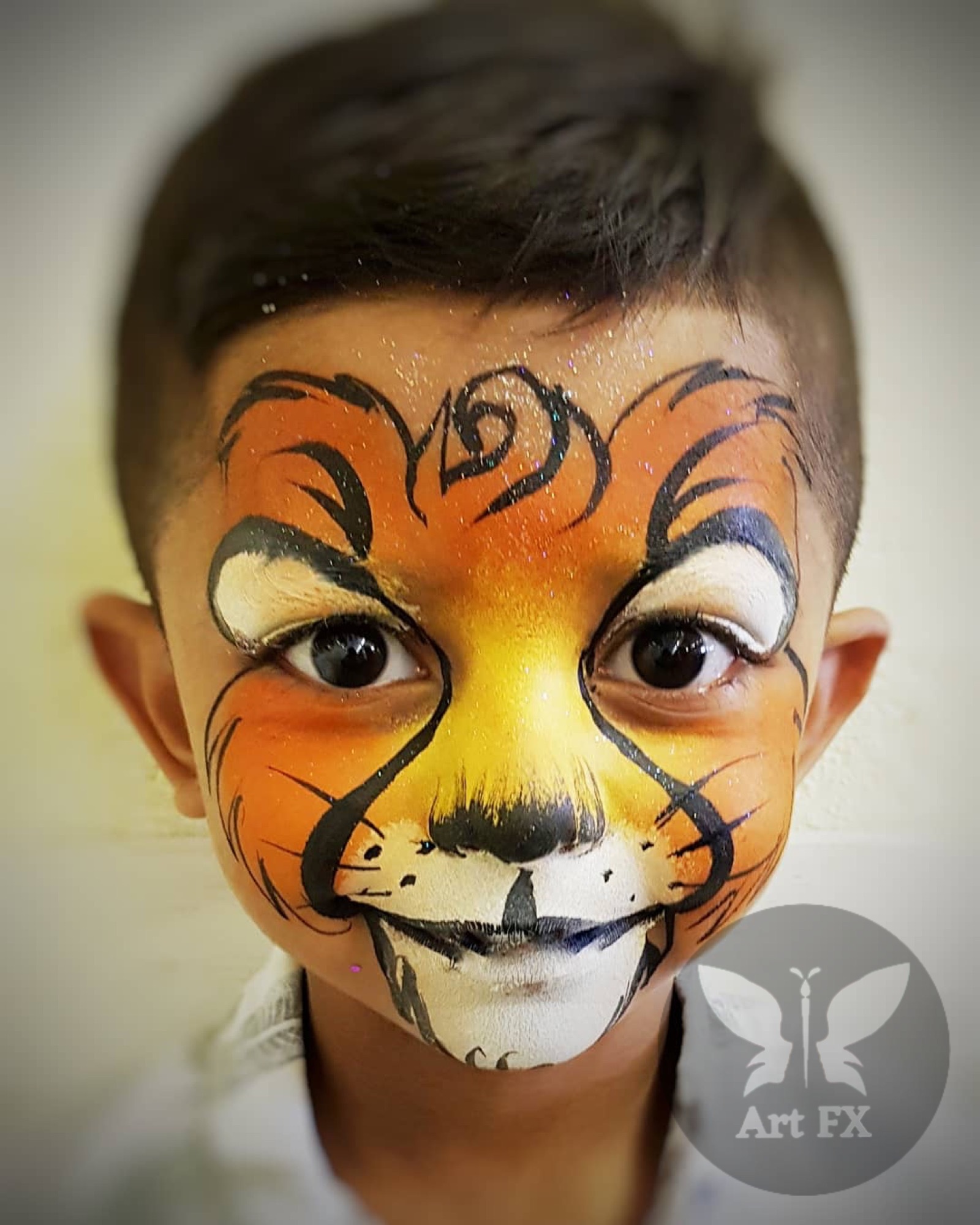 Young boy displaying a green superhero mask face painting design