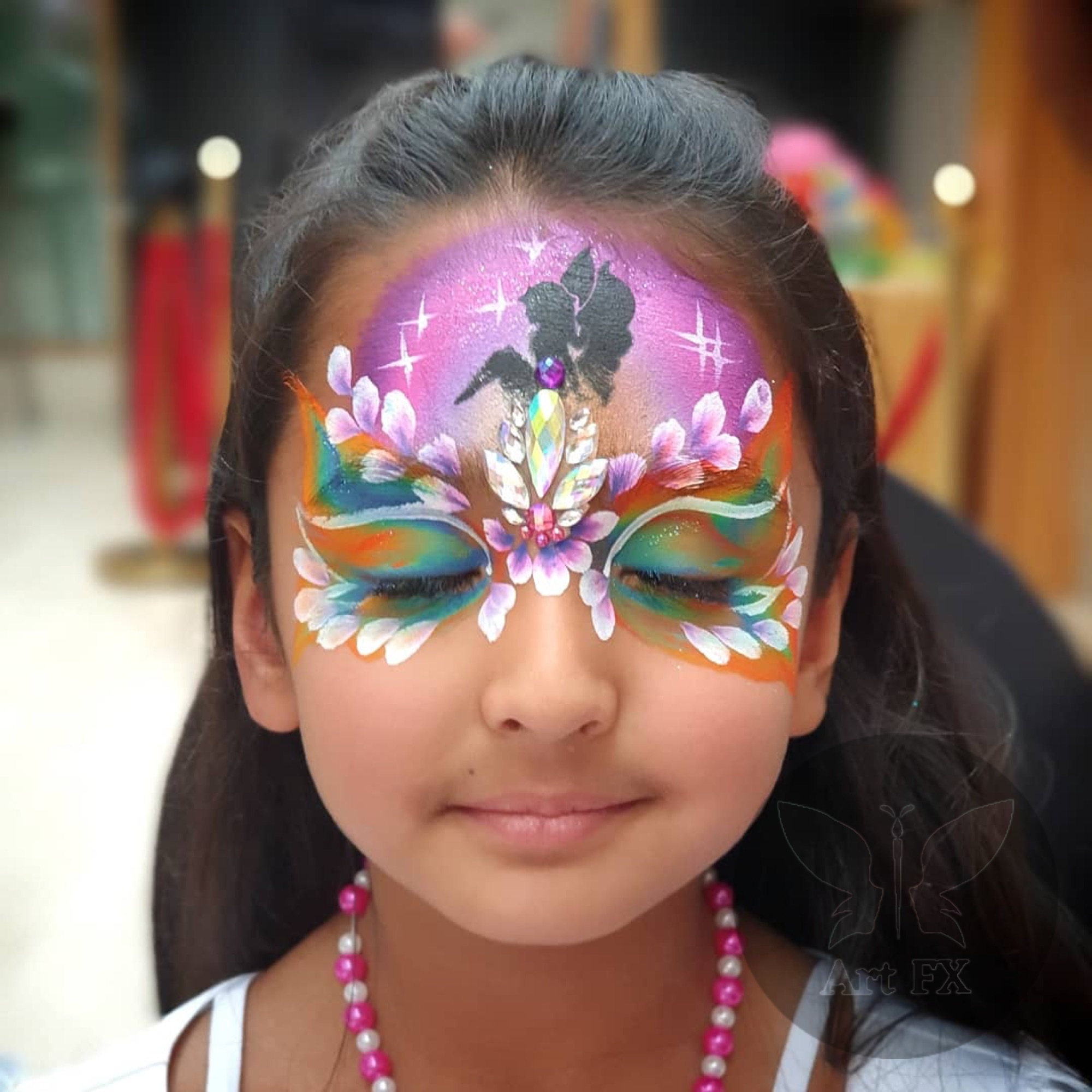Young girl with a rainbow butterfly mask face painting design