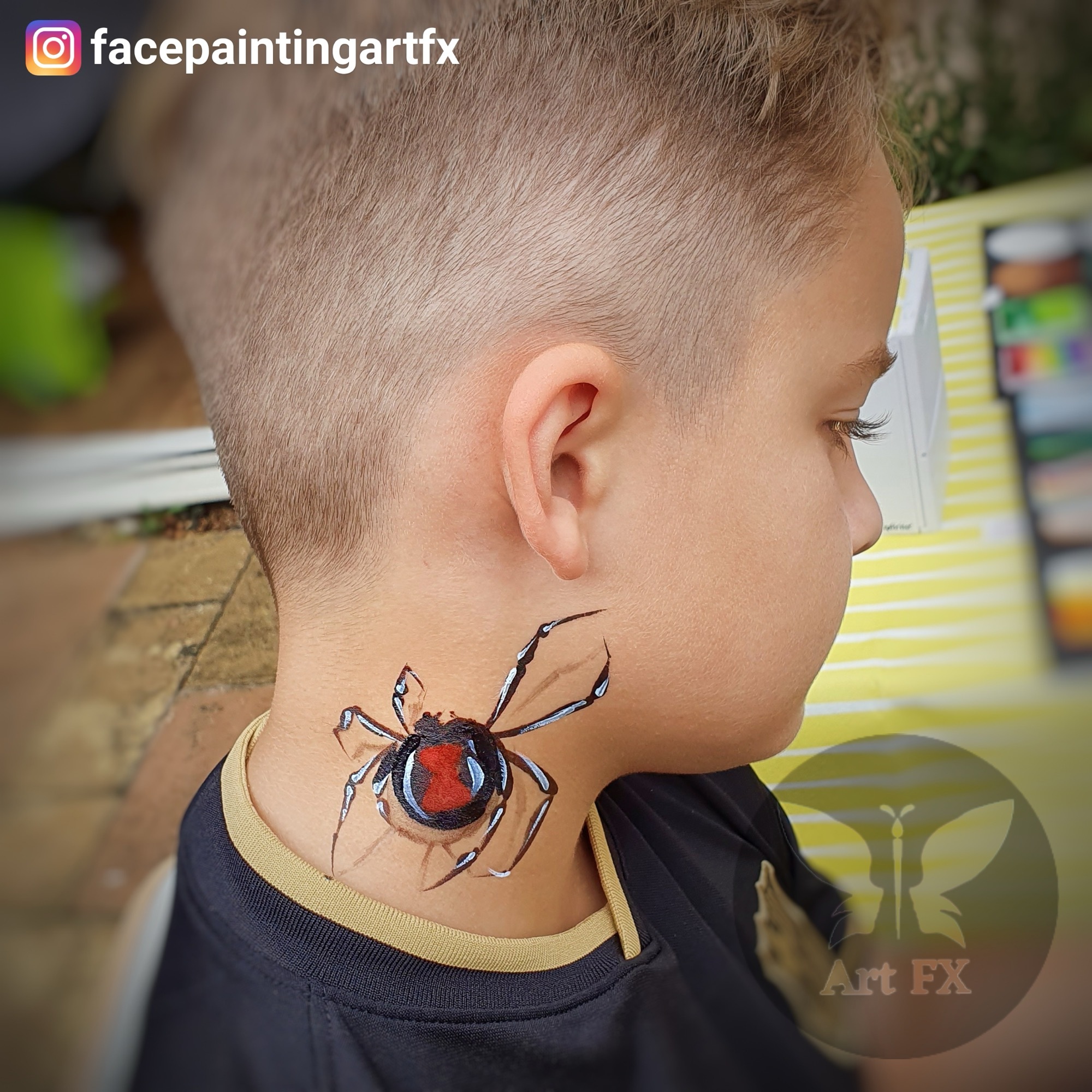 Young boy looking to the side showcasing a realistic 3D black and red spider face painting design on his neck