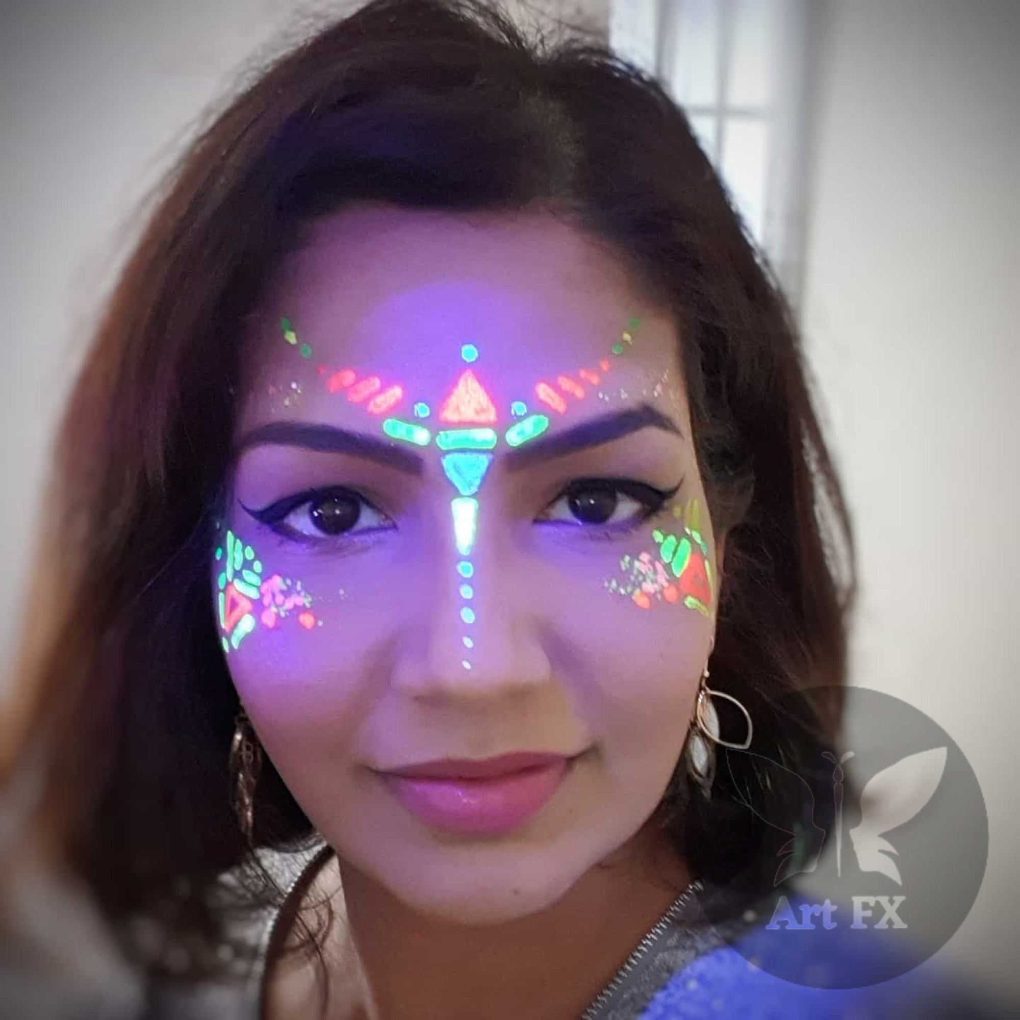 Neon star and swirl face painting design glowing bright under blacklight at a glow party