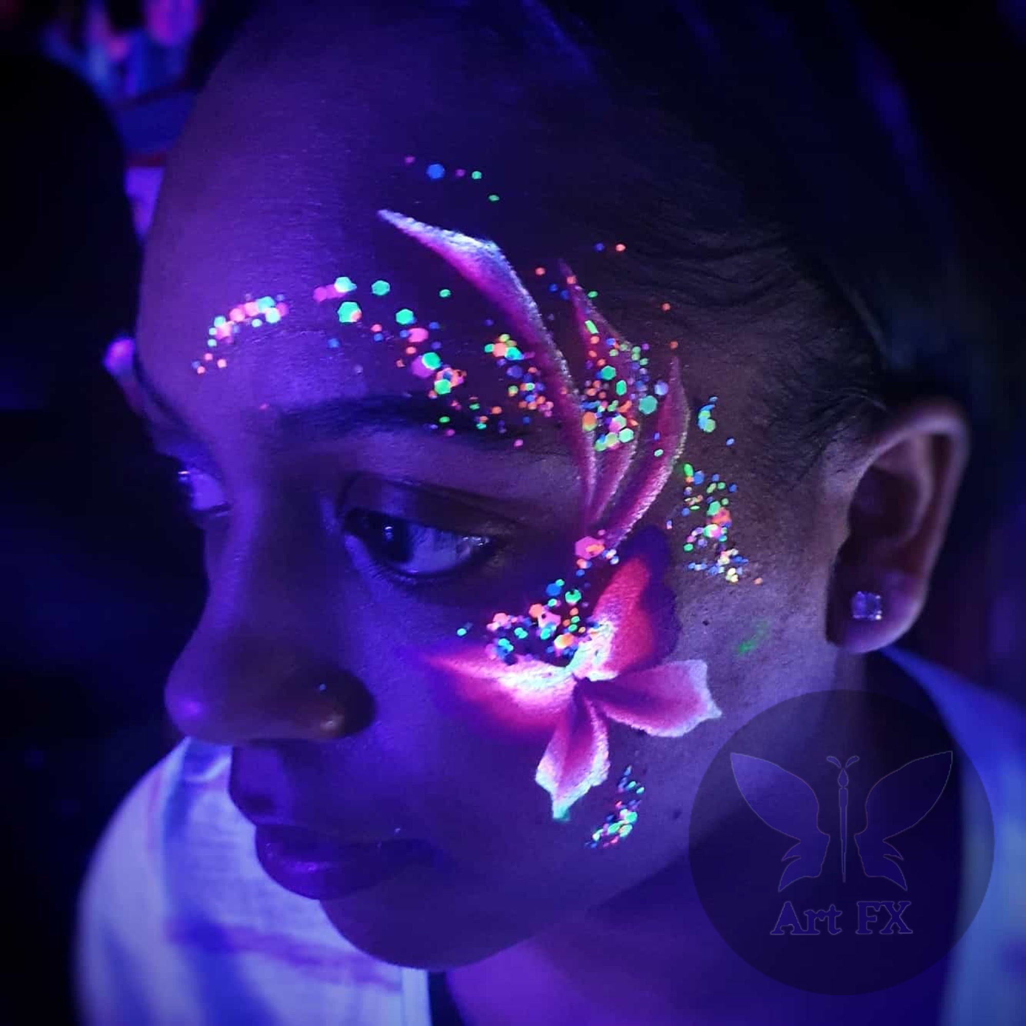 Glowing neon floral face painting with bright pink and green colors under UV blacklight